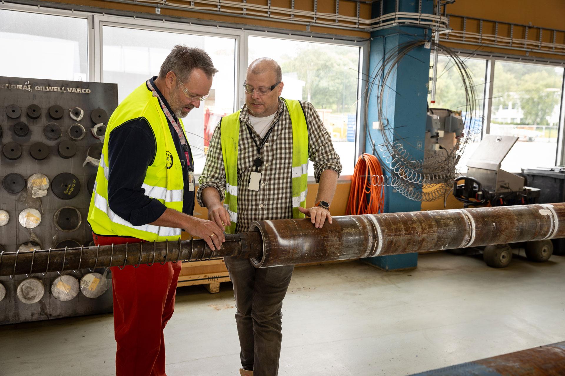 Mats and Oddbjorn closely inspecting and discussing a drill pipe