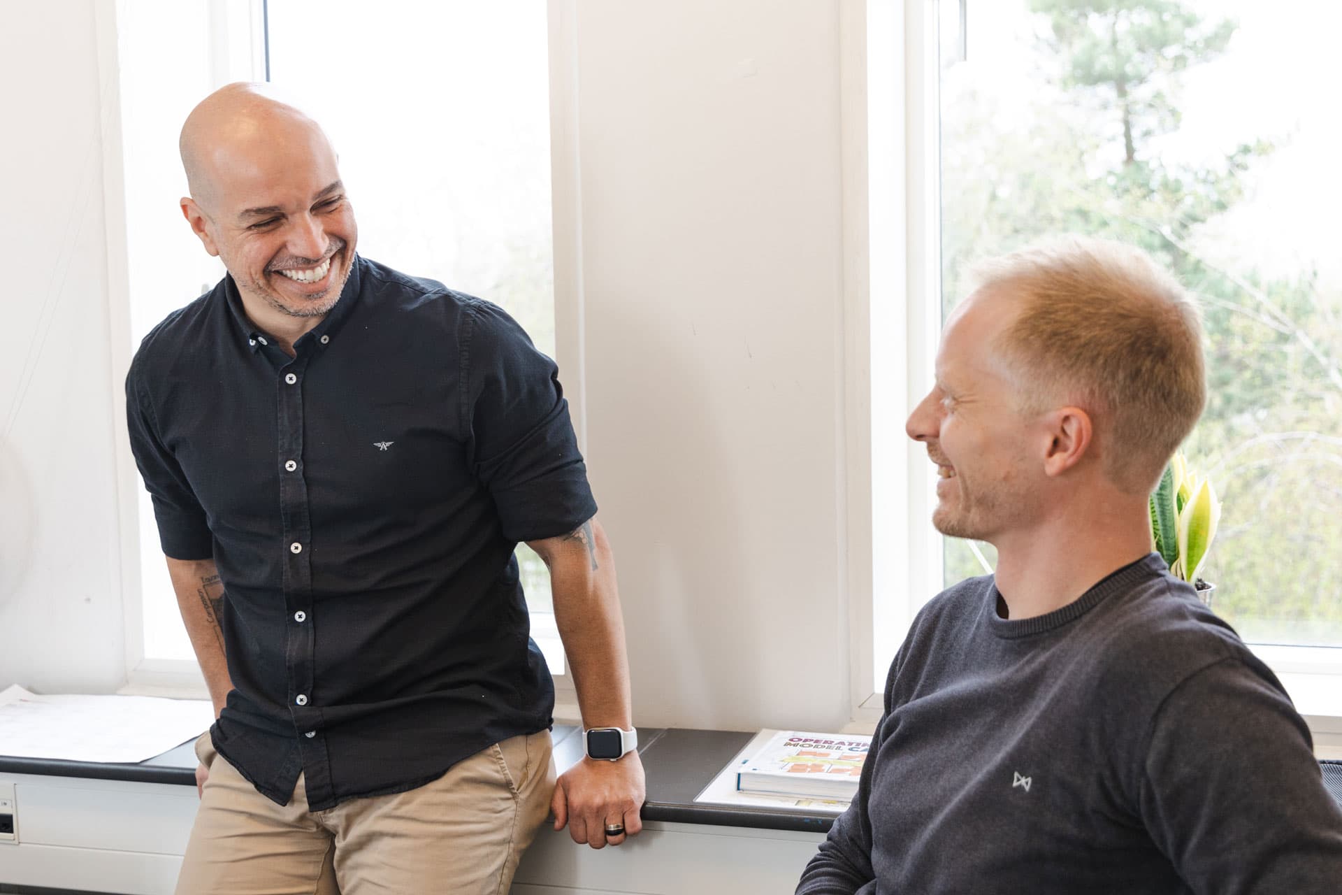 Two men in an office setting, chatting in a friendly manner