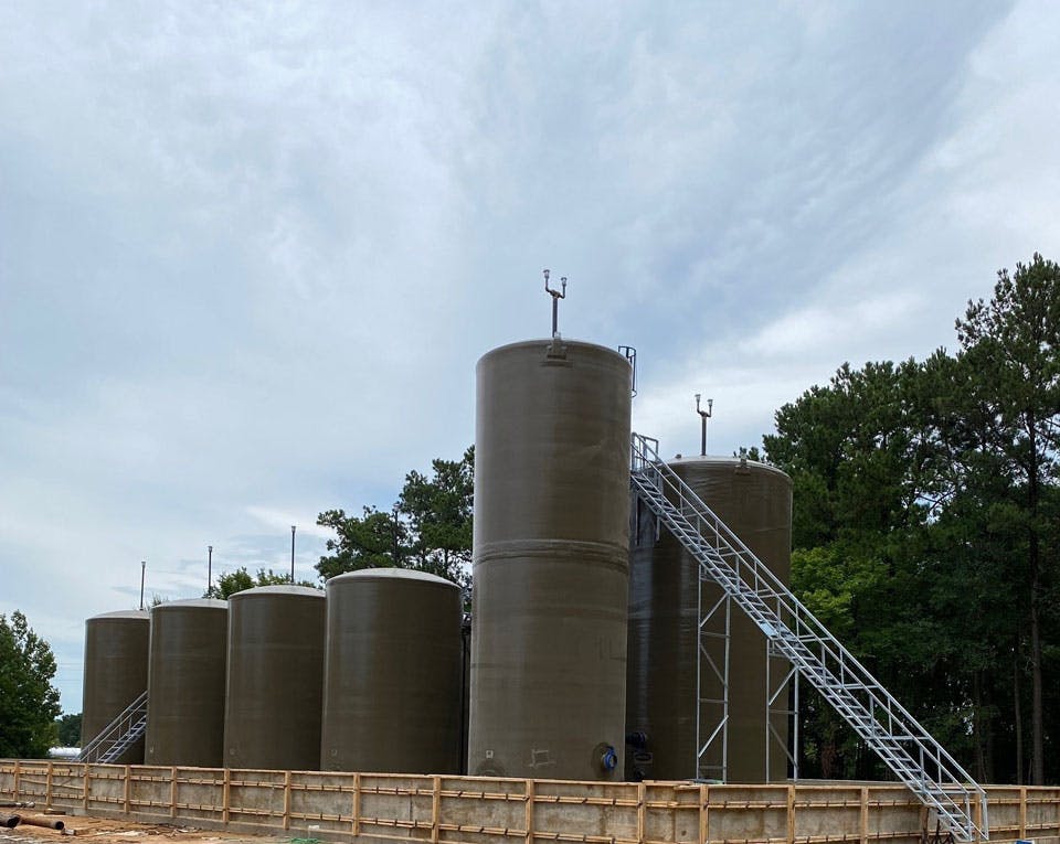 Fiberglass tanks for oil and gas exploration use, with trees in the background