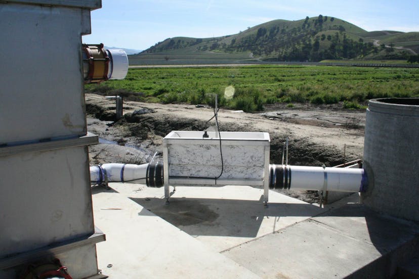 Palmer-Bowlus Flume connected to machinery, with grassy field and a mountain in the backgroumd