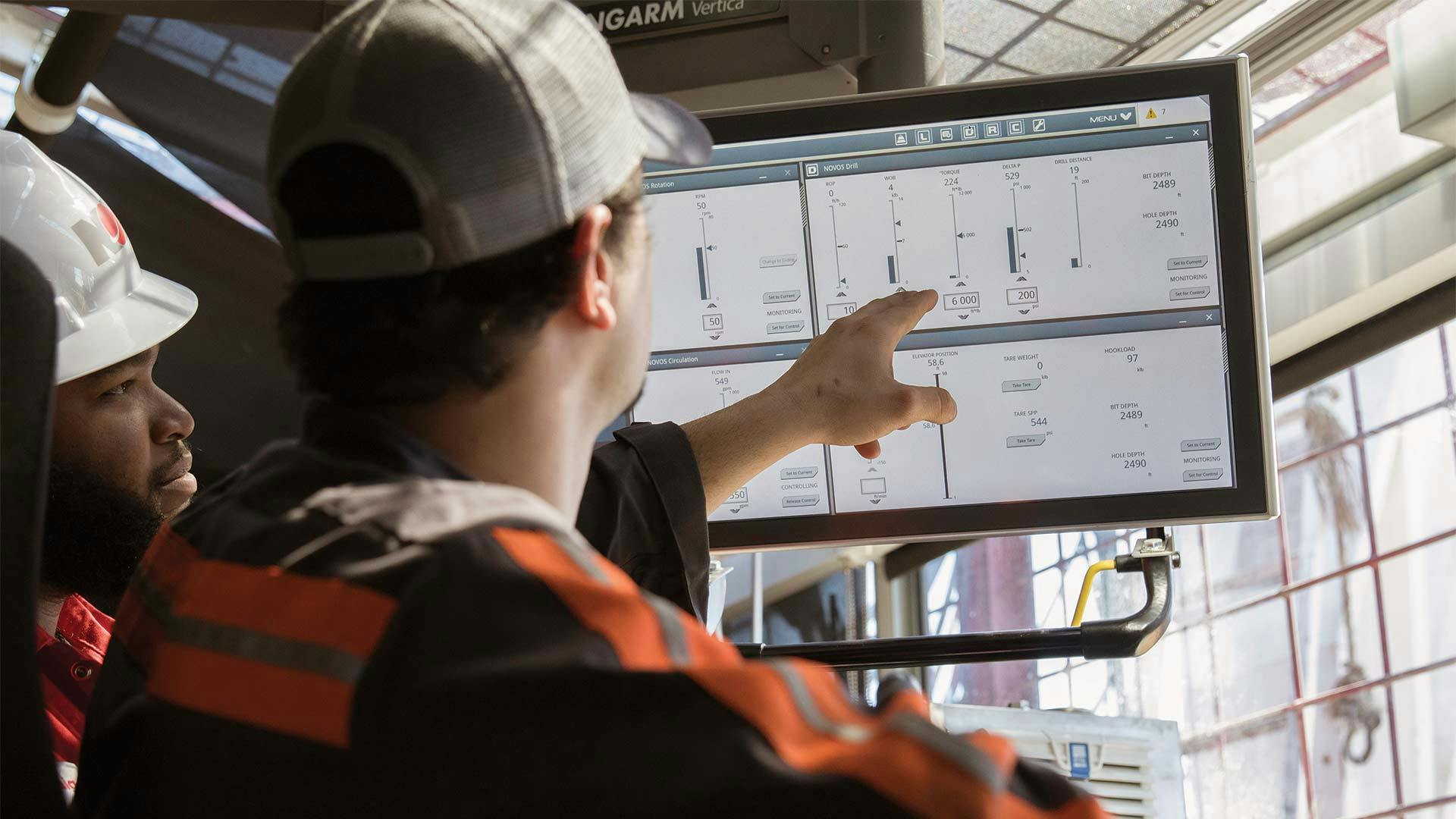 A rigger points to a screen running the NOVOS software system